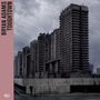 Text: "BRYAN ADAMS TOUGHTOWN". Massive, graue Hochhäuser vor bewölktem Himmel; einsame Person im Vordergrund., CD