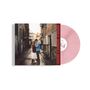 Eine rosa Vinylplatte mit Texten auf der Hülle. Ein Paar steht in einer schmalen, gepflasterten Gasse eng beieinander., LP