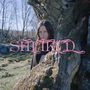 „SUFIKID“ in rosa Schrift zentriert. Ein Mensch steht teilweise verdeckt hinter einem Baumstamm in einer bewaldeten Landschaft., CD