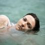 Eine Person mit nassem Haar liegt entspannt im Wasser, ihr Gesicht zeigt einen ruhigen Ausdruck., LP