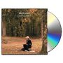 "John Greaves, Chansons d'Automne." Eine Frau in Herbstkleidung sitzt auf einem Stuhl im Wald, neben einer Wiese., CD