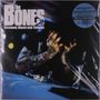 „The Bones, Screwed, Blued and Tattooed“. Tätowierte Person verdeckt Gesicht mit Händen, bläuliche Beleuchtung., LP