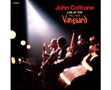 "John Coltrane Live at the Village Vanguard". Silhouetten von Musikern im Rampenlicht, vor beleuchtetem Hintergrund.