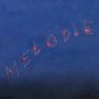 Der Text "MELODIE" ist aus roten Lichtern vor blauem Hintergrund geformt, wie Feuerwerkskörper.