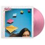Text: "Reaching for the Sky". Oben eine Person mit dunklem Haar, farbige Papierstücke davor. Pinke Vinyl-Schallplatte.
