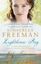 Texte: „warmly emotional“ Publishers Weekly, „a compelling story“ Canberra Times. Name: Kimberley Freeman. Titel: Lighthouse Bay. Untertitel: A century-old mystery will ultimately reveal the power of forgiveness. Eine Frau mit braunen Haaren, hellem Hintergrund mit Gras.