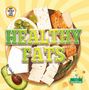 "HEALTHY FATS" in großer Schrift. Ein Brett mit Käse, Lachs, Oliven und einem Avocado-Bild darunter., Buch