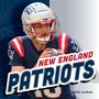 "New England Patriots" in markanten Buchstaben. Ein Footballspieler in blauer Ausrüstung hält einen Ball., Buch