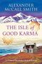 Titel: „The Isle of Good Karma“. Autor: Alexander McCall Smith. Illustration mit Haus vor Küstenlandschaft und Bergkulisse.