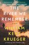 Text: "New York Times Bestseller. The River We Remember. A Novel. William Kent Krueger. Author of This Tender Land."  
Eine Person steht vor einem ruhigen Fluss bei Sonnenuntergang.