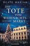„Die Tote vom Weihnachtsmarkt“ von Beate Maxian. Ein geschmückter Weihnachtsbaum vor einem beleuchteten Gebäude., Buch