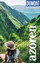 "DUMONT Reise-Taschenbuch" oben und "Azoren" vertikal. Eine Person mit Hut sitzt vor grünen Bergen., Buch