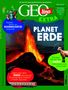 Titel: "PLANET ERDE". Vulkan mit Lavaausbruch, umgeben von Grün und Texten über Bodenschätze, Ziegen und Erdbeben., Buch
