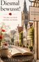 "Diesmal bewusst! Von dem, was bleibt und dem, was kommt." Ein Buch liegt auf einem Tisch, dahinter eine malerische Altstadt., Buch