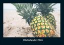 "Obstkalender 2026" in weißem Text. Zwei Ananas auf hellem Sandstrand liegend.