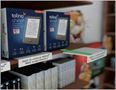 "Jetzt in unserer kleinen Welt angekommen." Ein Regal mit E-Reader-Verpackungen und Büchern., Buch