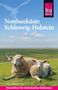 "Nordseeküste Schleswig-Holstein" sind die Wörter oben. Zwei Schafe liegen auf einer grünen Wiese mit blauem Himmel., Buch