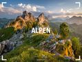 „ALPEN 2027“ steht im Vordergrund einer malerischen Berglandschaft mit felsigen Gipfeln und üppigem Grün im Abendlicht.