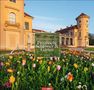 "Leo Seidel: Ein Spaziergang durch Preußische Schlösser & Gärten 2027." Vor einem Schloss mit bunten Blumenbeeten.
