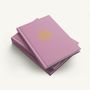 Pinkes Buch mit der Aufschrift "2027", einem goldenen Muster und Text "Flower of Life." Aufeinandergestapelt., Buch