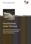Titel: "Constitutions under Pressure". Dominosteine, eine Waage und Richterhammer im Hintergrund.