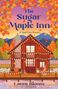 "The Sugar Maple Inn: A Small-Town Romance" von Laura Bloom. Illustration eines Holzhauses in Herbstlandschaft mit Lichtern.