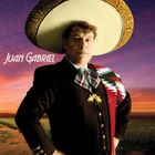 „Juan Gabriel“ in weißer Schrift. Person in traditioneller Kleidung und großem Hut vor farbigem, abendlichen Himmel.
