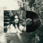 Eine unscharfe Frau sitzt auf einer Treppe mitten im Wald, neben ihr eine schwarze Schallplatte.