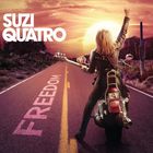 "SUZI QUATRO" und "FREEDOM" sind zu sehen. Eine Frau auf einem Motorrad erhebt die Faust auf einer Landstraße im Sonnenuntergang.