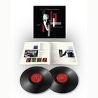 "MIDGE URE Chapters: The Best Of" steht auf einem Plattencover mit schwarzem Hintergrund. Unten sind zwei Vinyl-Schallplatten und ein aufgeschlagenes Booklet.