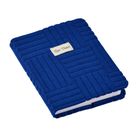 Ein Notizbuch mit Text "Quo Vadis" auf einer strukturierten, blauen Stoffhülle.