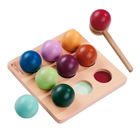 Holzspielbrett mit runden, bunten Bällen in Halterungen und ein hölzerner Hammer daneben.