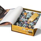 Eine Schachtel mit Puzzle-Teilen, der Deckel zeigt Illustrationen und Text wie "Beth Gilbert" und "Fourth Wing".