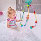 Keine erkennbaren Texte. Ein kleines Kind spielt in der Badewanne mit bunten Schläuchen, trägt gestreiften Badeanzug.