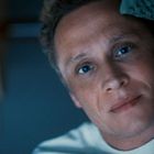 Es sind keine Texte im Bild enthalten. Ein Mann liegt seitlich und blickt freundlich mit leichtem Lächeln in die Kamera.