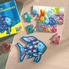Text: „Der Regenbogenfisch“. Ein Puzzle zeigt bunte Fische. Ein weiteres Puzzle in Form eines blauen Fisches liegt daneben.