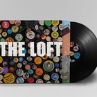 "The Loft" in großen weißen Buchstaben. Bunte Buttons auf einer Jeansjacke. Schallplatte sichtbar.