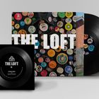 "The Loft" in großen Buchstaben auf einem Plattencover voller bunter Buttons. Eine Schallplatte ist sichtbar.
