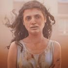 Ich kann keine Texte oder Copyright-Informationen erkennen. Eine Frau mit verwuscheltem Haar und schmutzigem Hemd wirkt erschöpft.