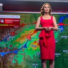 "Wettervorhersage für Kansas City mit Farben von leicht bis stark, Frau in rotem Kleid steht vor Wetterkarte."