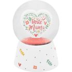 Herz mit Text "Beste Mama" in bunter, floraler Illustration in einer Schneekugel auf weißem Sockel mit Mustern.