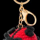 Ein goldener Schlüsselring mit einem kleinen gehäkelten Marienkäfer-Anhänger in Rot und Schwarz.