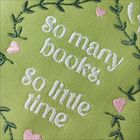 „So many books, so little time“ steht in Weiß auf grünem Stoff mit pinken Herzen und grünen Blättern.