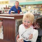 "Homemade Pies - Pastries - Cakes" steht auf einem Schild. Eine Frau wird in einem Diner von einer anderen Person angegriffen.