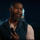 Kein Text zu erkennen. Ein lächelnder Mann hält ein Smartphone, im Hintergrund ist die Freiheitsstatue bei Nacht zu sehen.