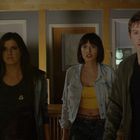 Drei Menschen stehen in einem Raum, blicken überrascht. Links ein Monitor.