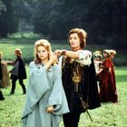 Text: "aamni". Zwei junge Menschen, ein Mann und eine Frau, tanzen auf einer Wiese, umgeben von anderen Personen.