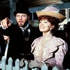 Ein Mann zeigt in die Ferne, neben ihm eine Frau im eleganten, historischen Kostüm. Beide wirken fröhlich.