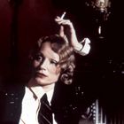 Eine Frau im Retro-Stil sitzt nachdenklich mit Zigarette in der Hand. Sie trägt Anzug und Krawatte.