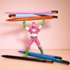 Zu sehen sind Kugelschreiber mit "CEDON" und eine Spielzeugfigur, die sie balanciert. Die Figur trägt rosa und grün.